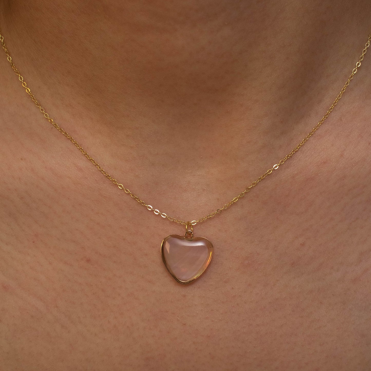 This photo showcases a thin chain necklace with 14K gold  plated Sterling Silver, paired with a heart-shaped pendant made of pearl paper. 