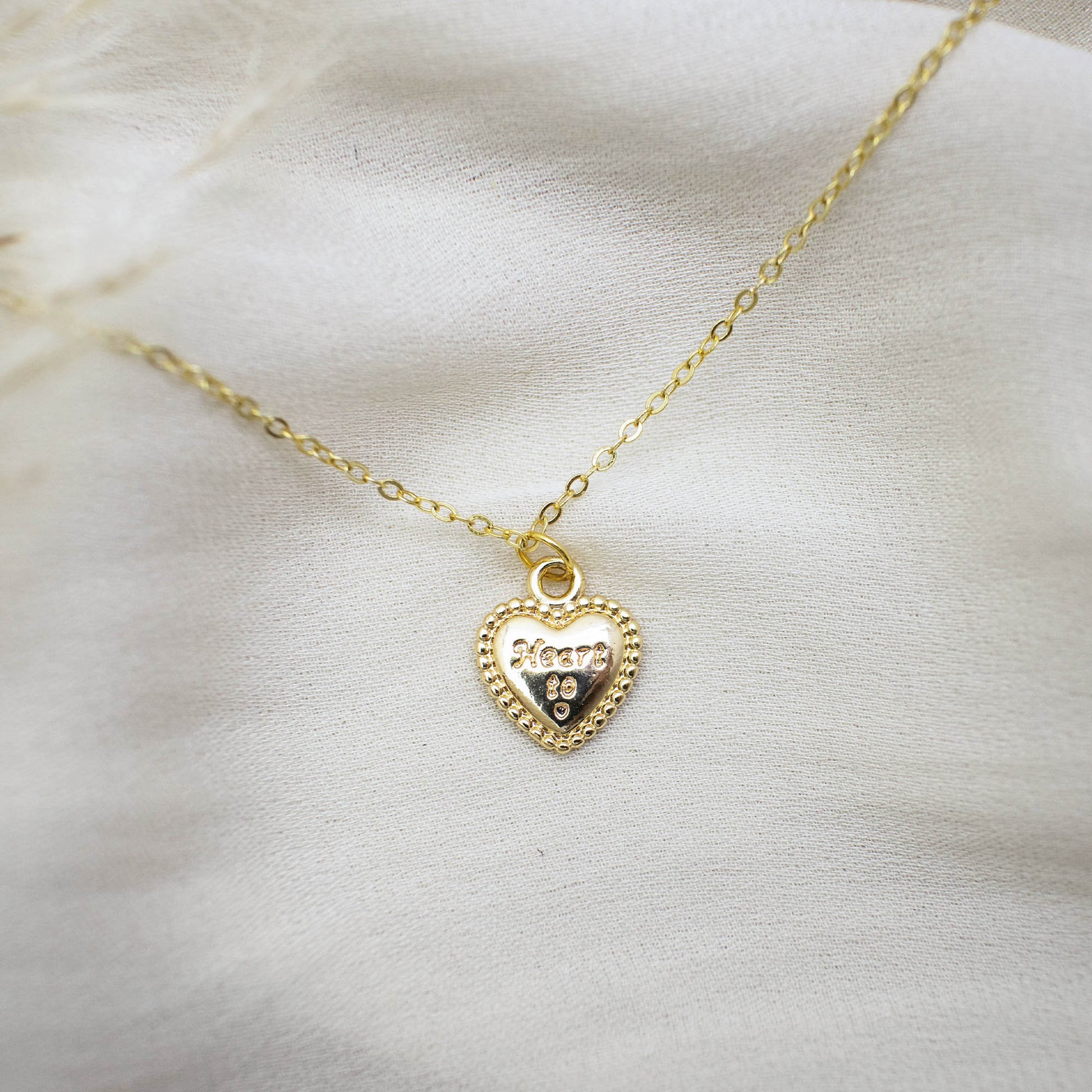 A Necklace made by 14K gold-plated brass, paired with a heart-shaped pendant with the words 'Heart to'.