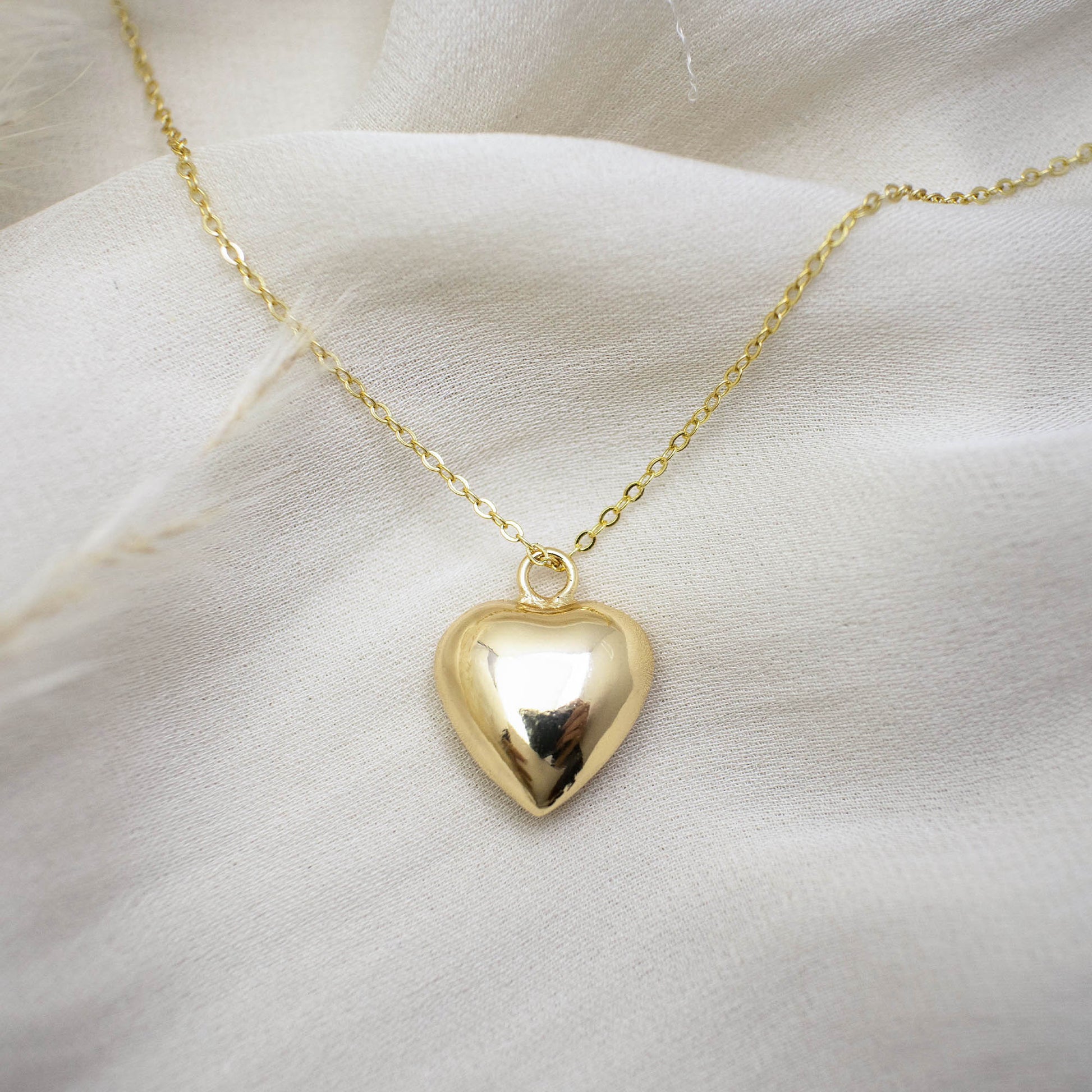 This photo features a thin chain necklace made of 14K gold-plated sterling silver, paired with a hollow heart-shaped charm.
