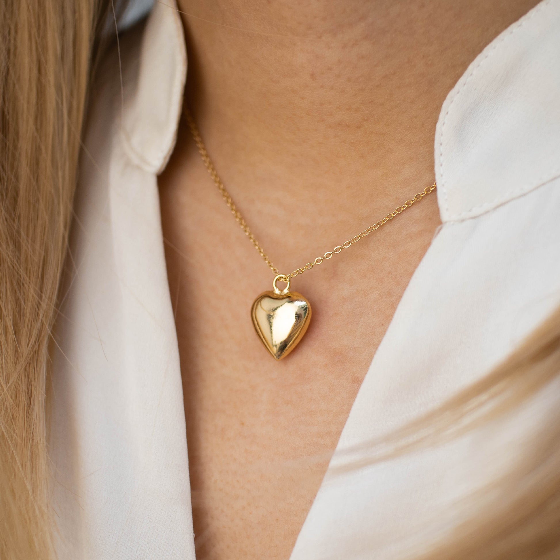 This photo features a thin chain necklace made of 14K gold-plated sterling silver, paired with a hollow heart  charm.