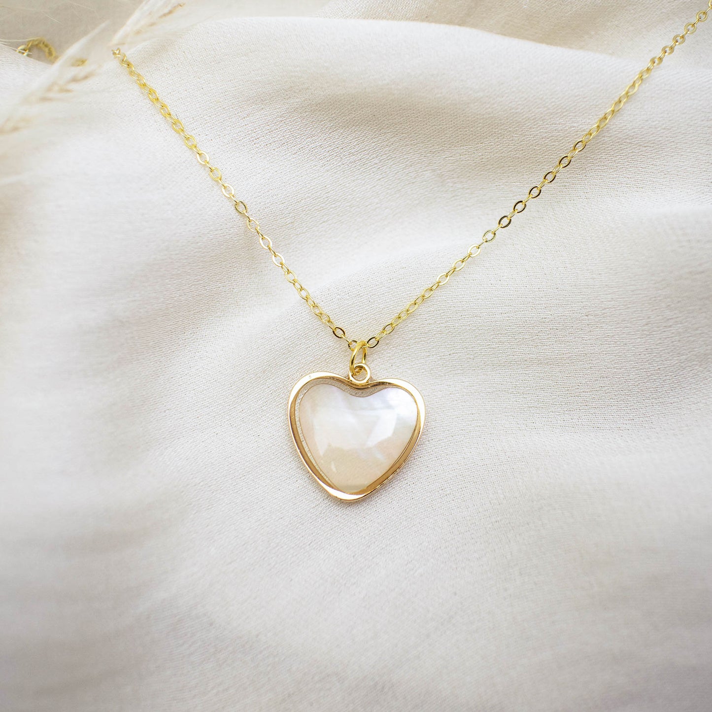 This photo showcases a thin chain necklace with 14K gold plated Sterling Silver, paired with a heart-shaped pendant made of pearl paper.