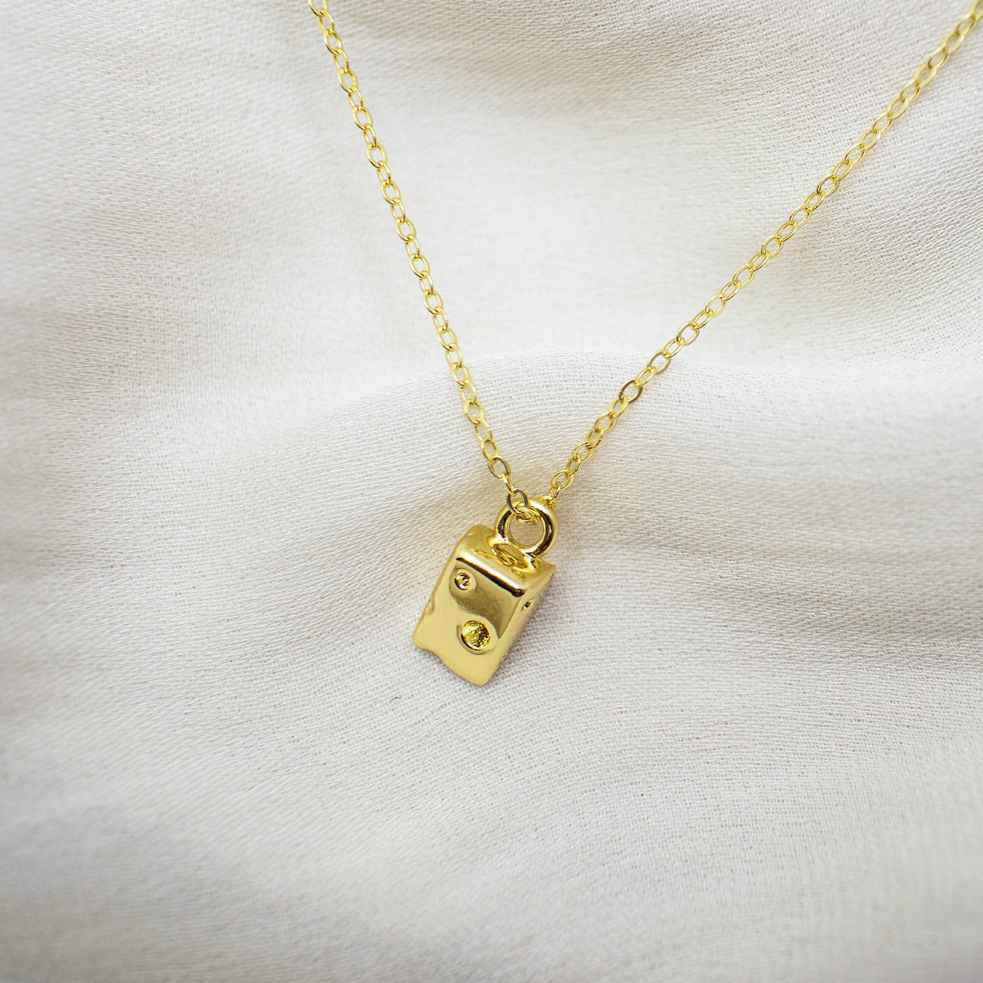 This photo features a thin chain necklace made of 14K gold-plated sterling silver, paired with a mini cheese pendant.