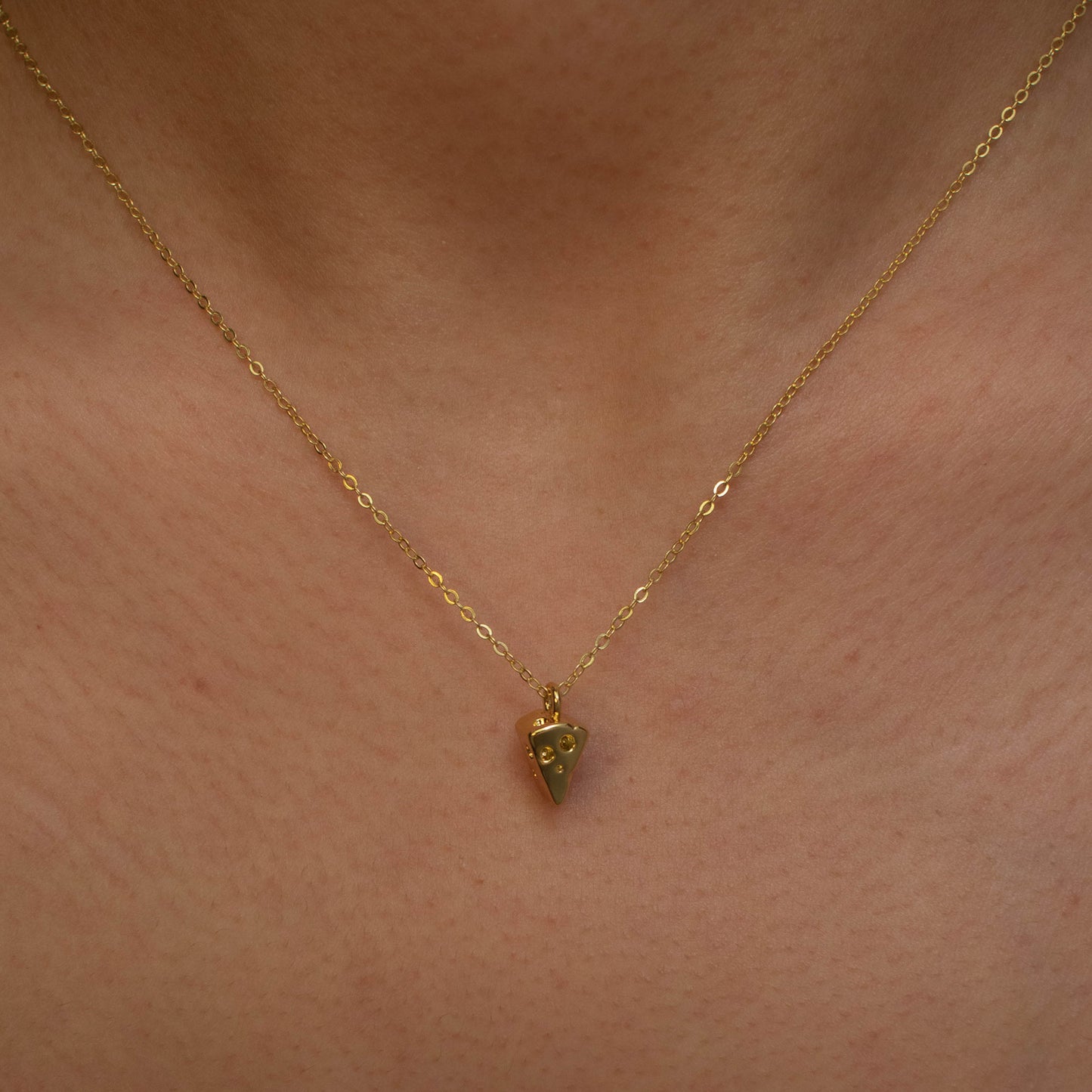 This photo features a thin chain necklace made of 14K gold-plated sterling silver, paired with a mini cheese pendant.