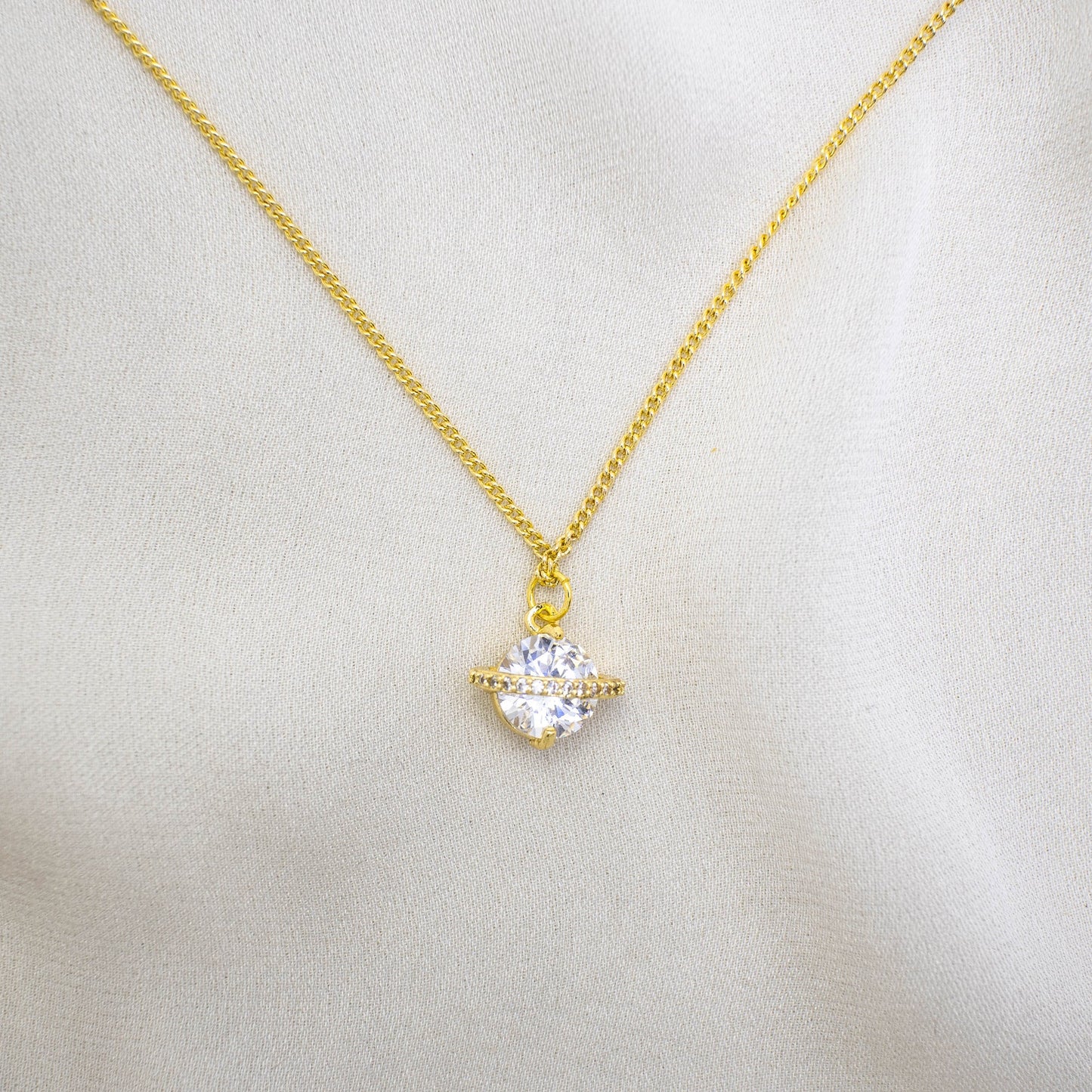 This photo features a thin chain necklace made of 14K gold-plated sterling silver, paired with a zircon planet charm.