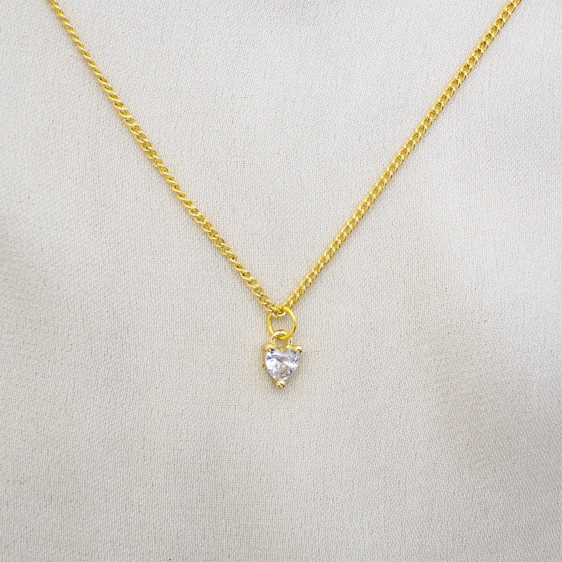 This photo features a thin chain necklace made of 14K gold-plated sterling silver, paired with a mini zirconia heart charm.