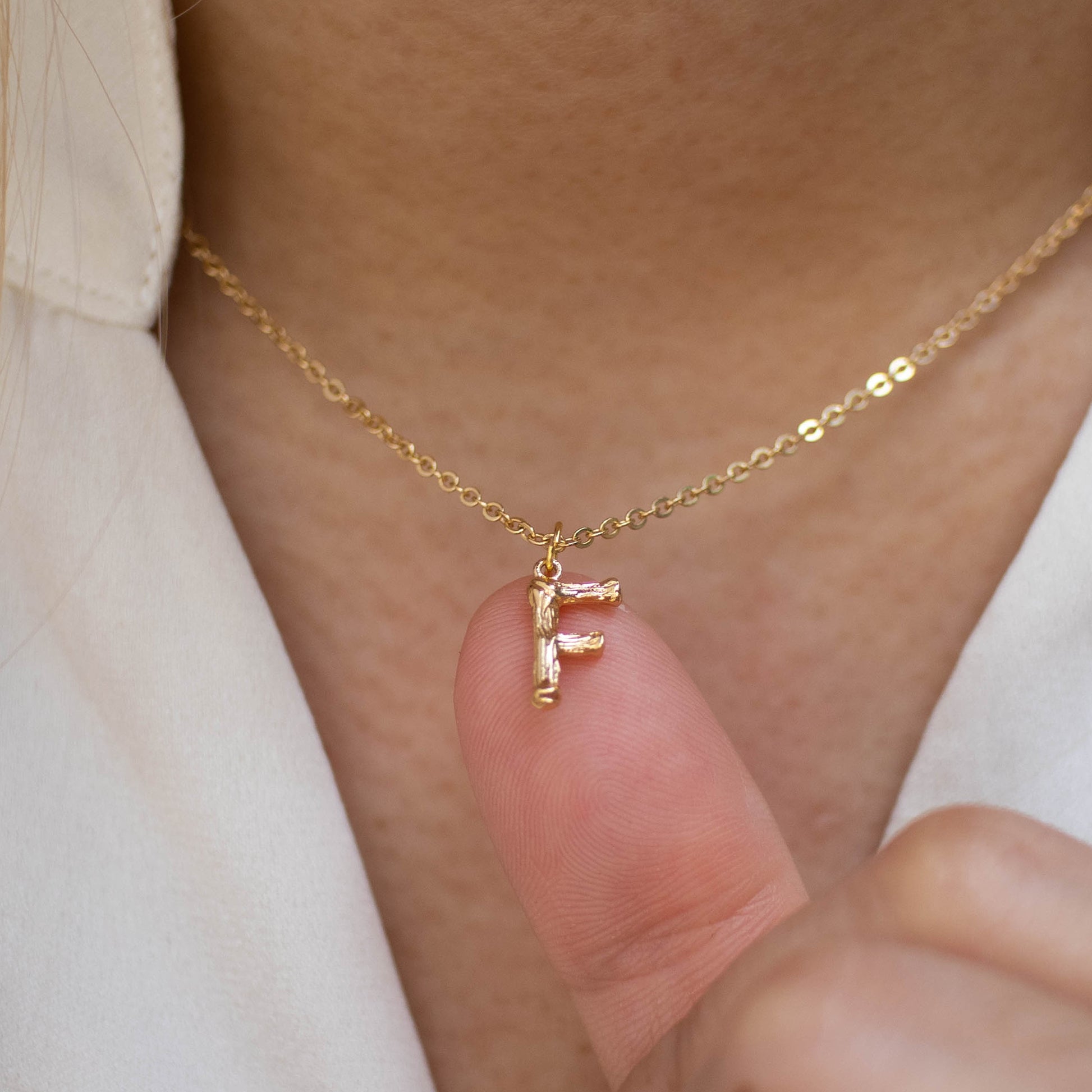 This photo features a thin chain necklace made of 14K gold-plated sterling silver, paired with a golden Letter pendant.