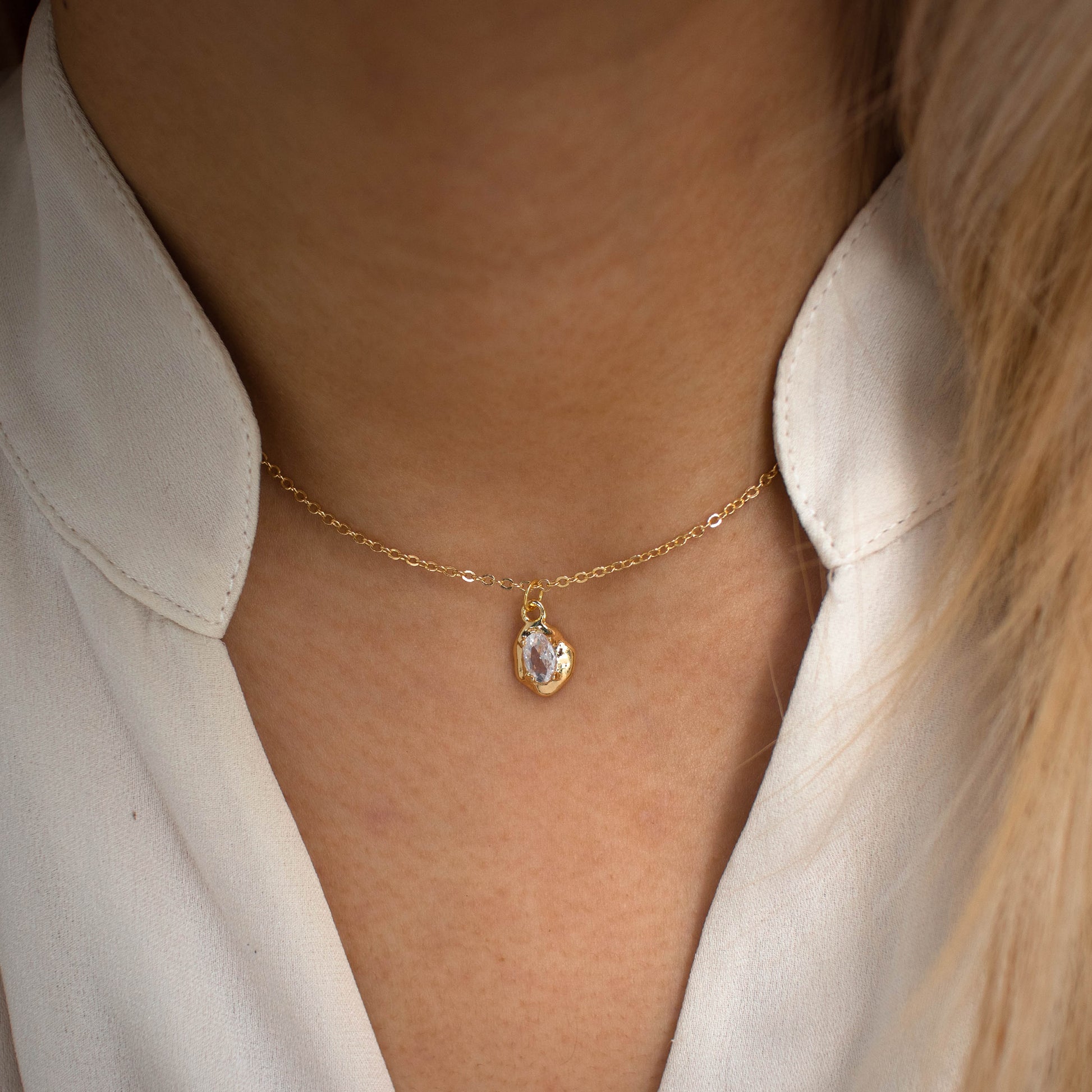 This photo features a thin chain necklace made of 14K gold-plated sterling silver, paired with a irregularly zircon.