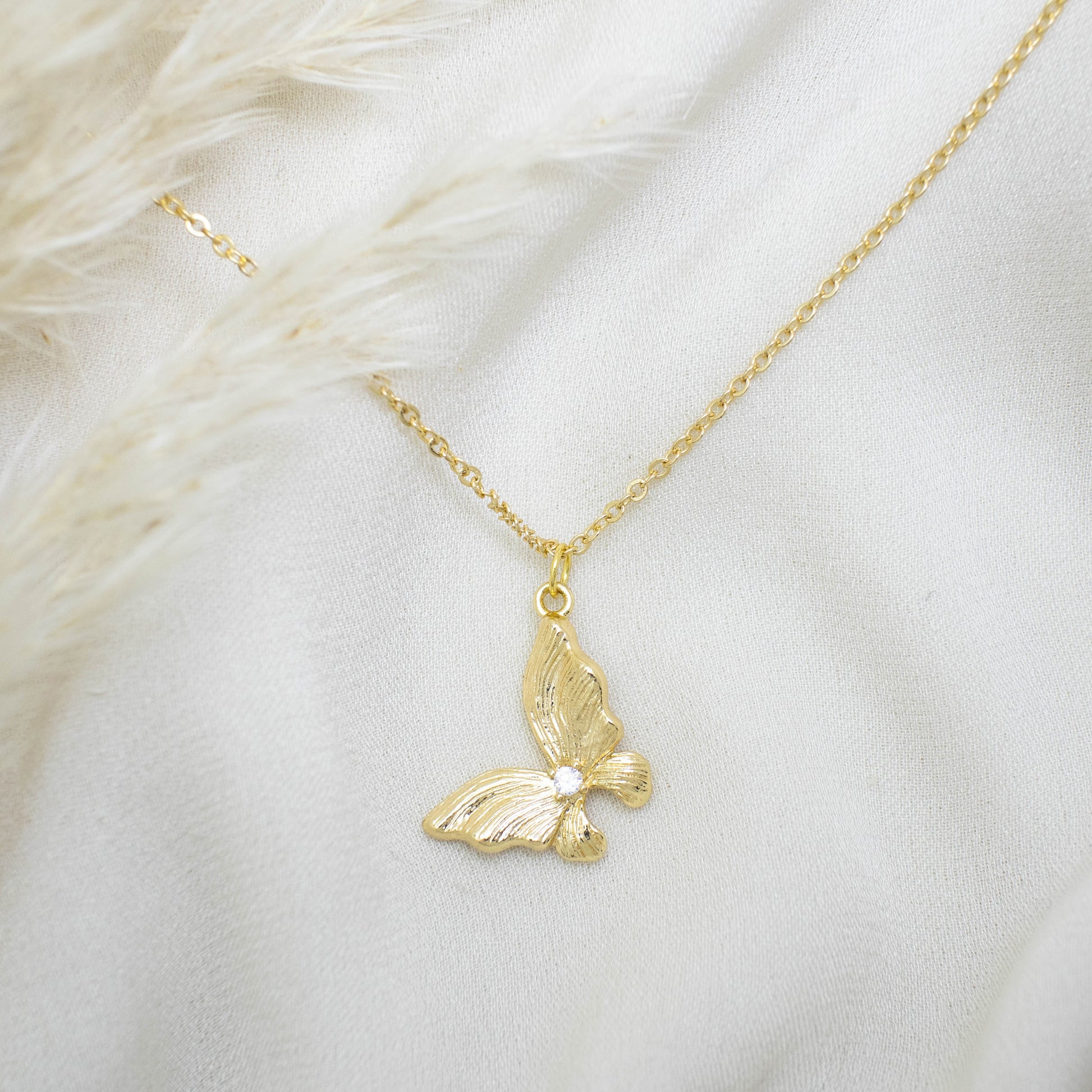 This photo features a thin chain necklace made of 14K gold-plated sterling silver, paired with Gold Butterfly Necklace